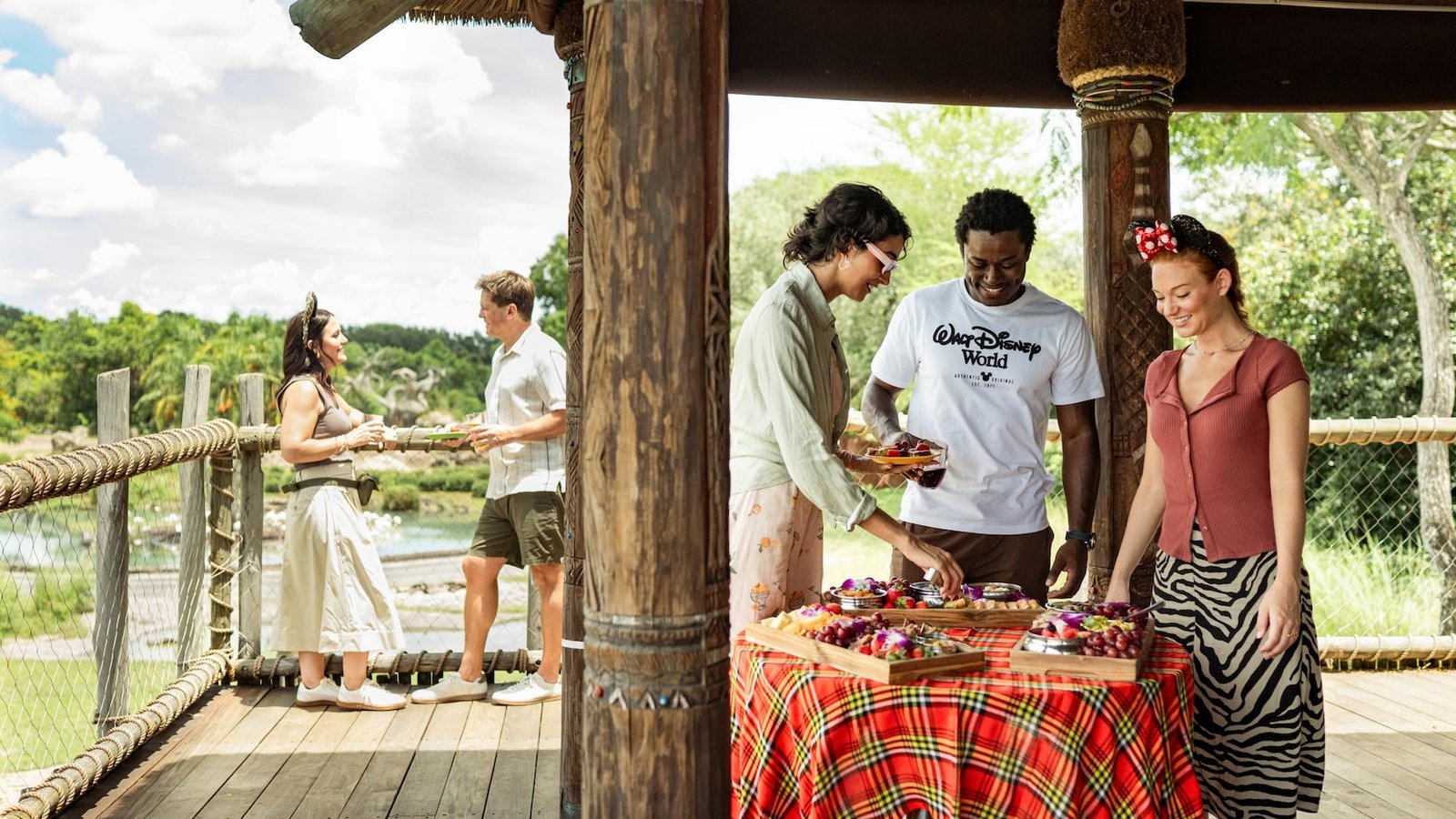 Guests socializing around a table of snacks at a patio in Harambe Wildlife Preserve