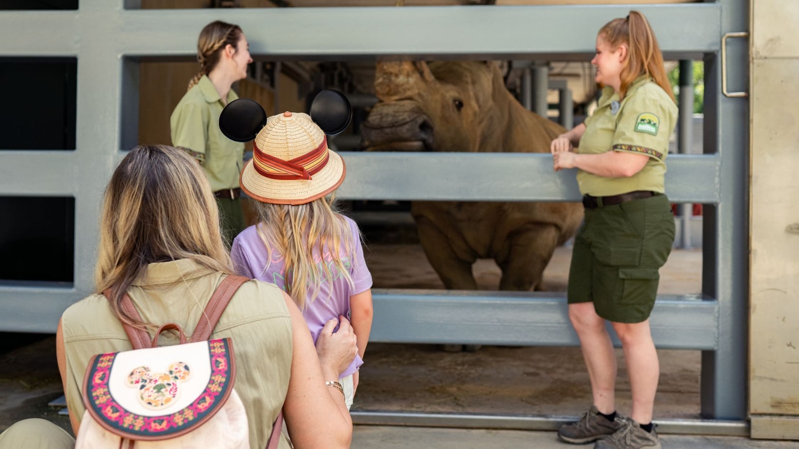 A woman and a young girl observe a rhinoceros through a gated enclosure at Disney’s Animal Kingdom Park