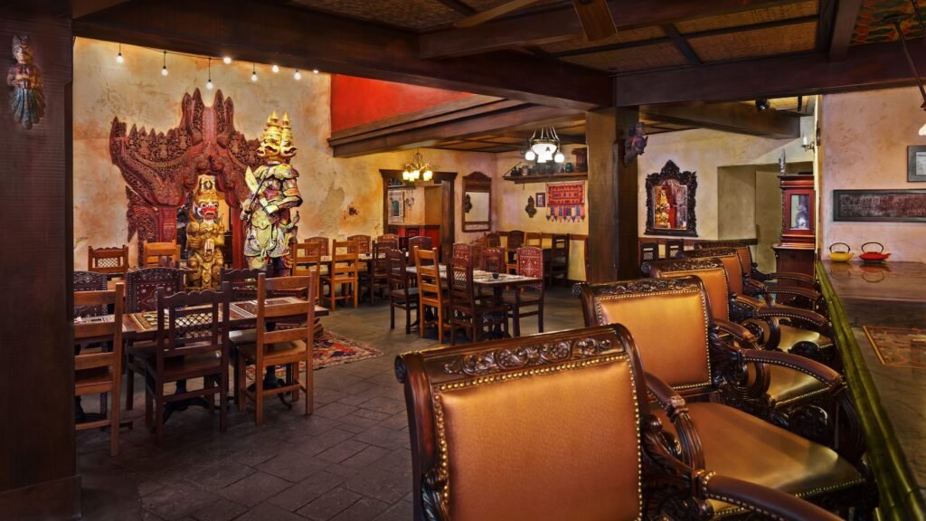 Dining room with Southeast Asian décor of wooden tables and carved chairs guarded by fierce statues